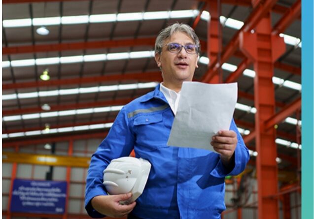 Facility engineer holding documents and a hard hat inside a site facility managed with construction stormwater compliance software.